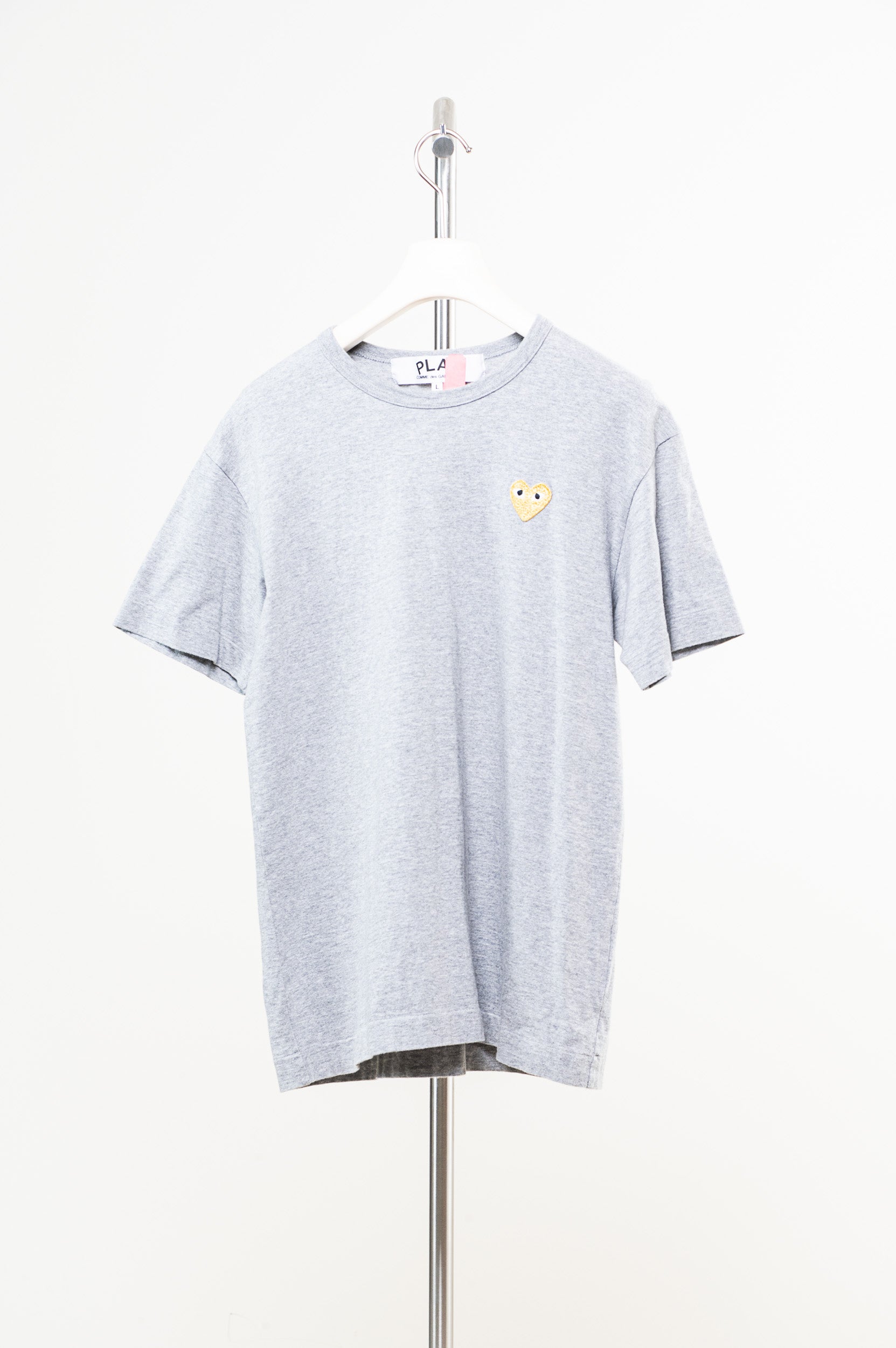 Front view of Comme Des Garçons grey tee with gold embossed logo