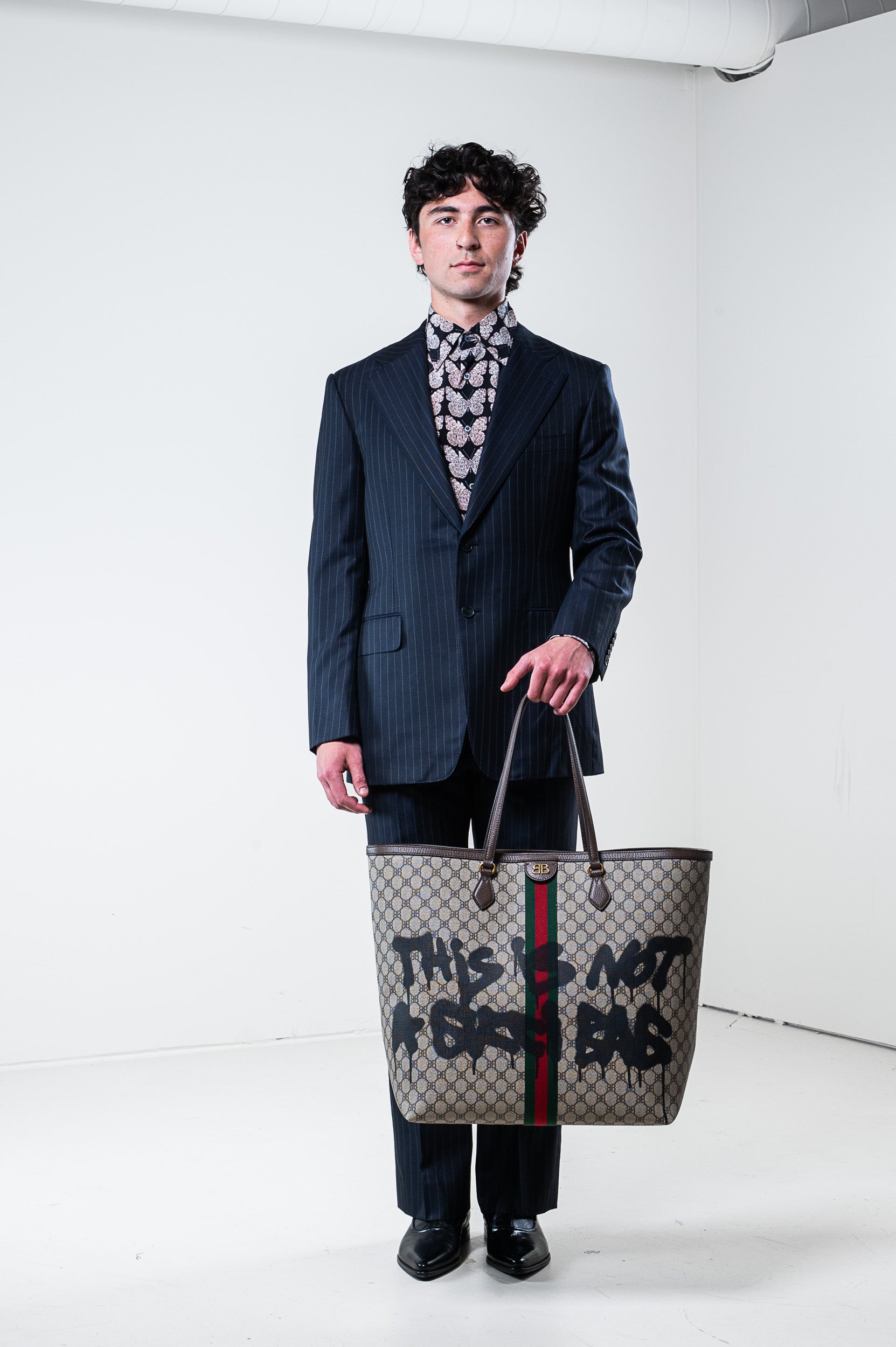 Model wearing Gucci silk butterfly shirt and carrying a bag