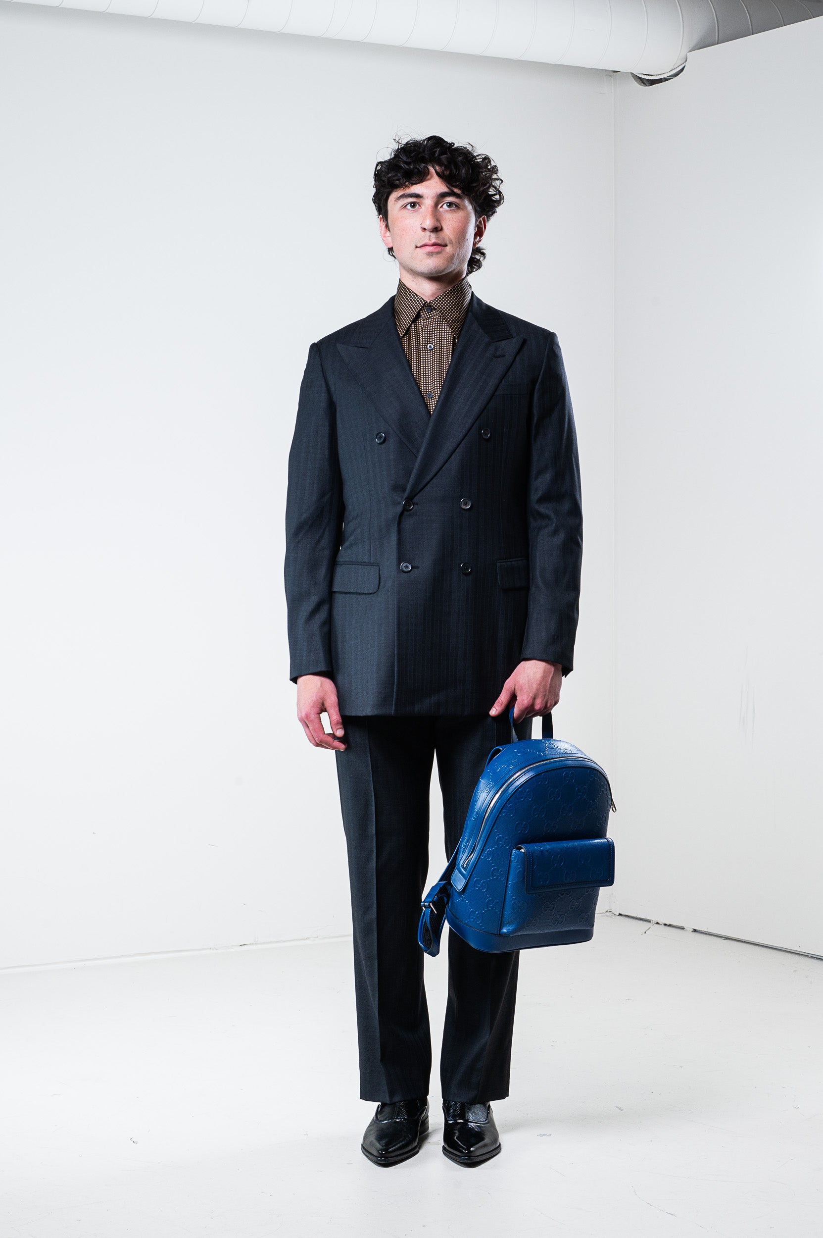 Model wearing Gucci silk patterned shirt and carrying a bag