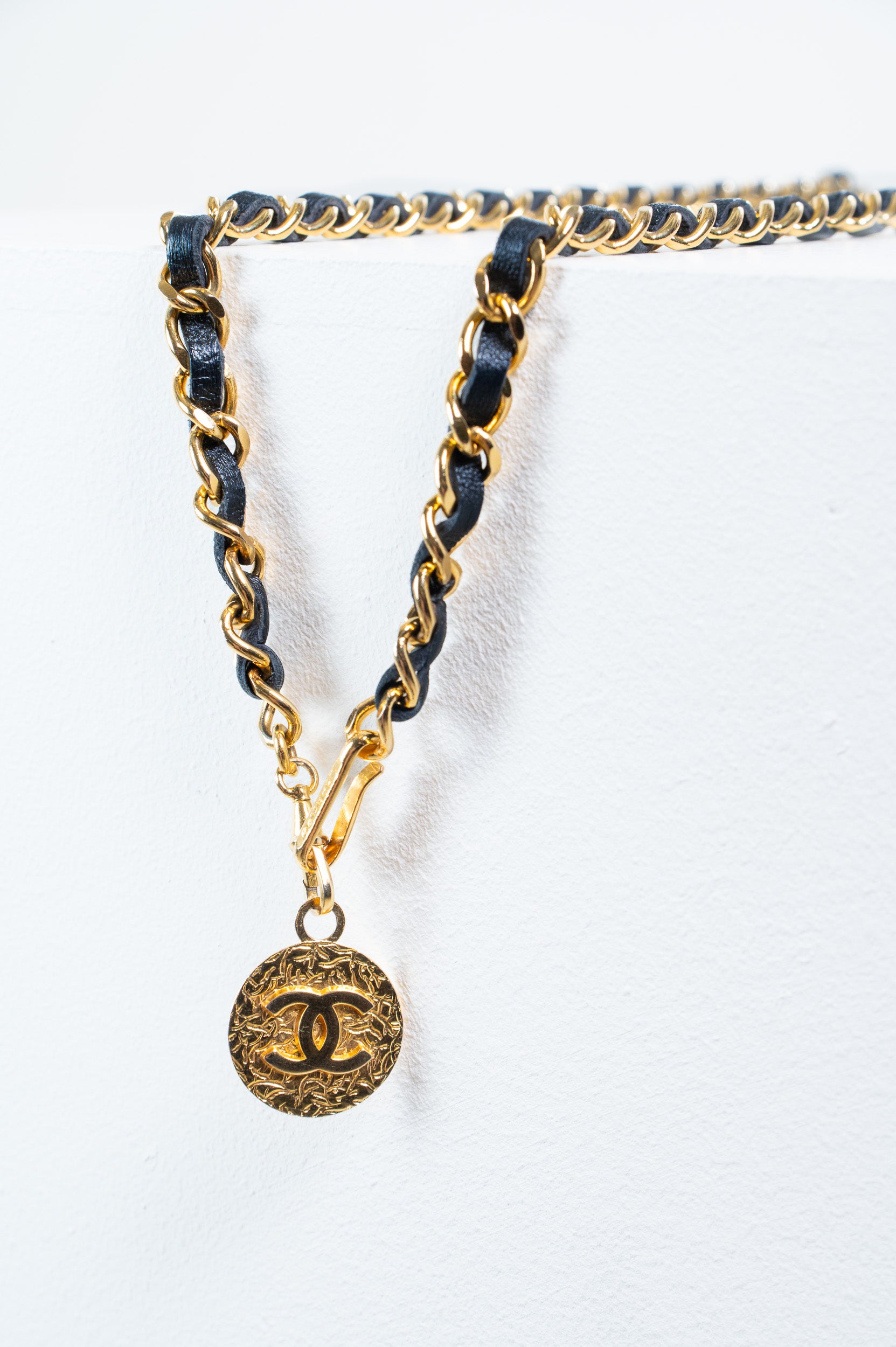 Detailed view of round gold medallion featuring Coco Chanel profile embossing