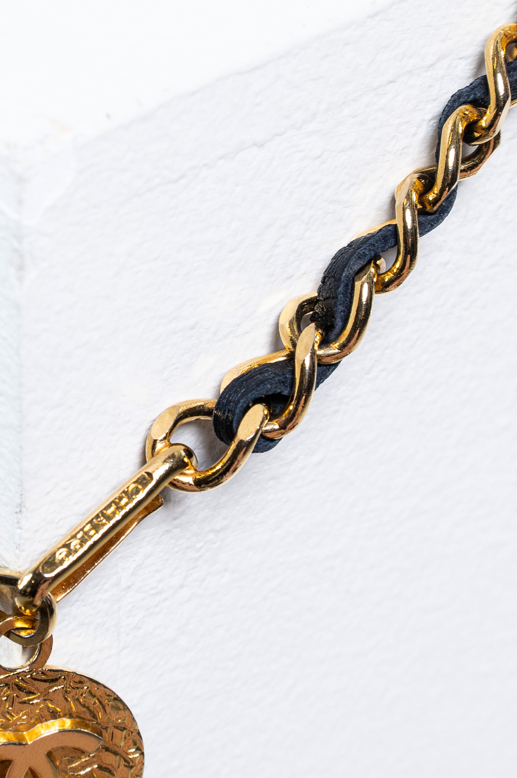 Close-up of interwoven black calfskin and gold-tone chain links