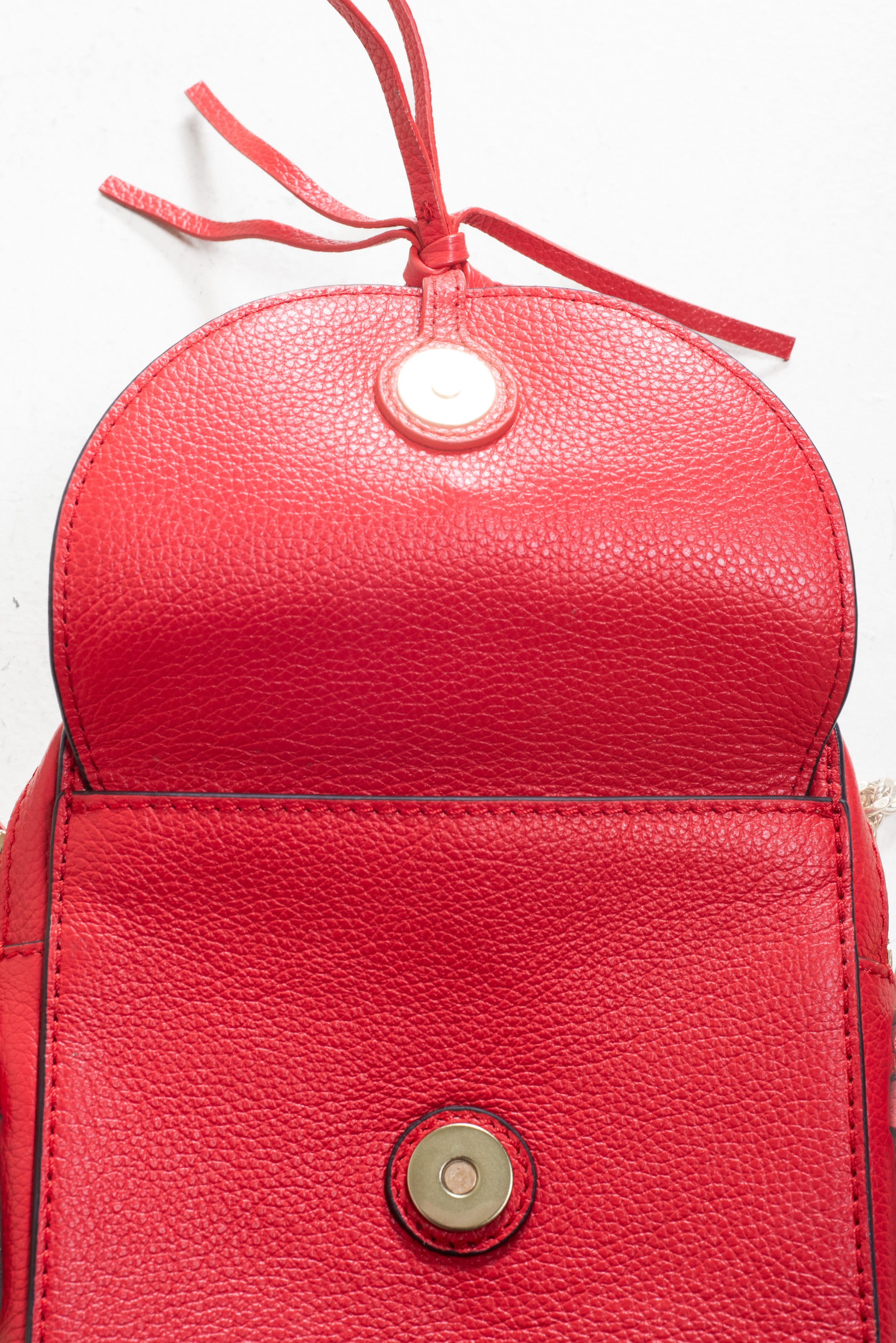 Close-up view of the interior leather surface revealed after opening the suede flap on the See by Chloé Small Red Joan Crossbody