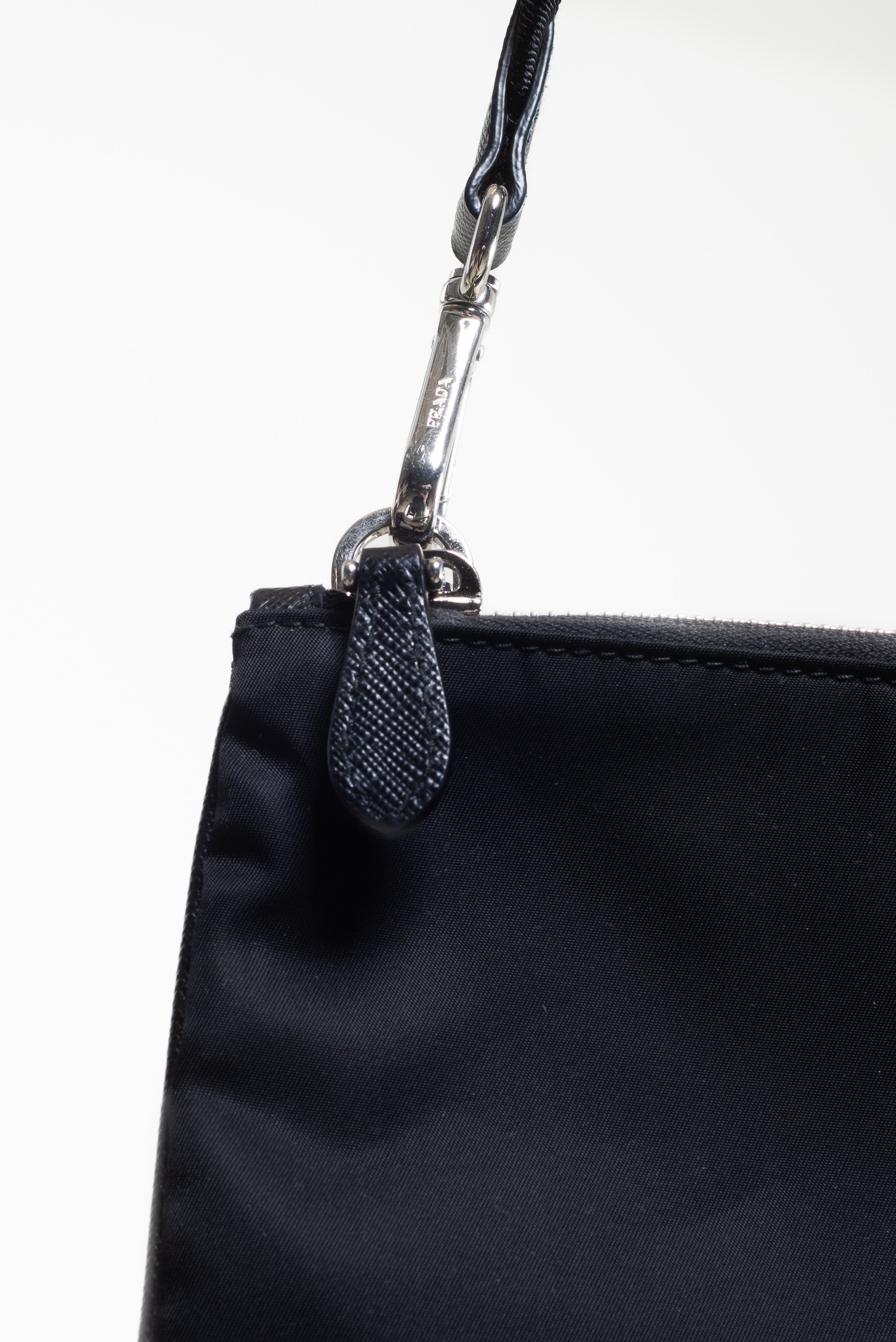 Detailed close-up of the strap connection hardware on the Prada Black Re-Nylon and Saffiano Crossbody Bag