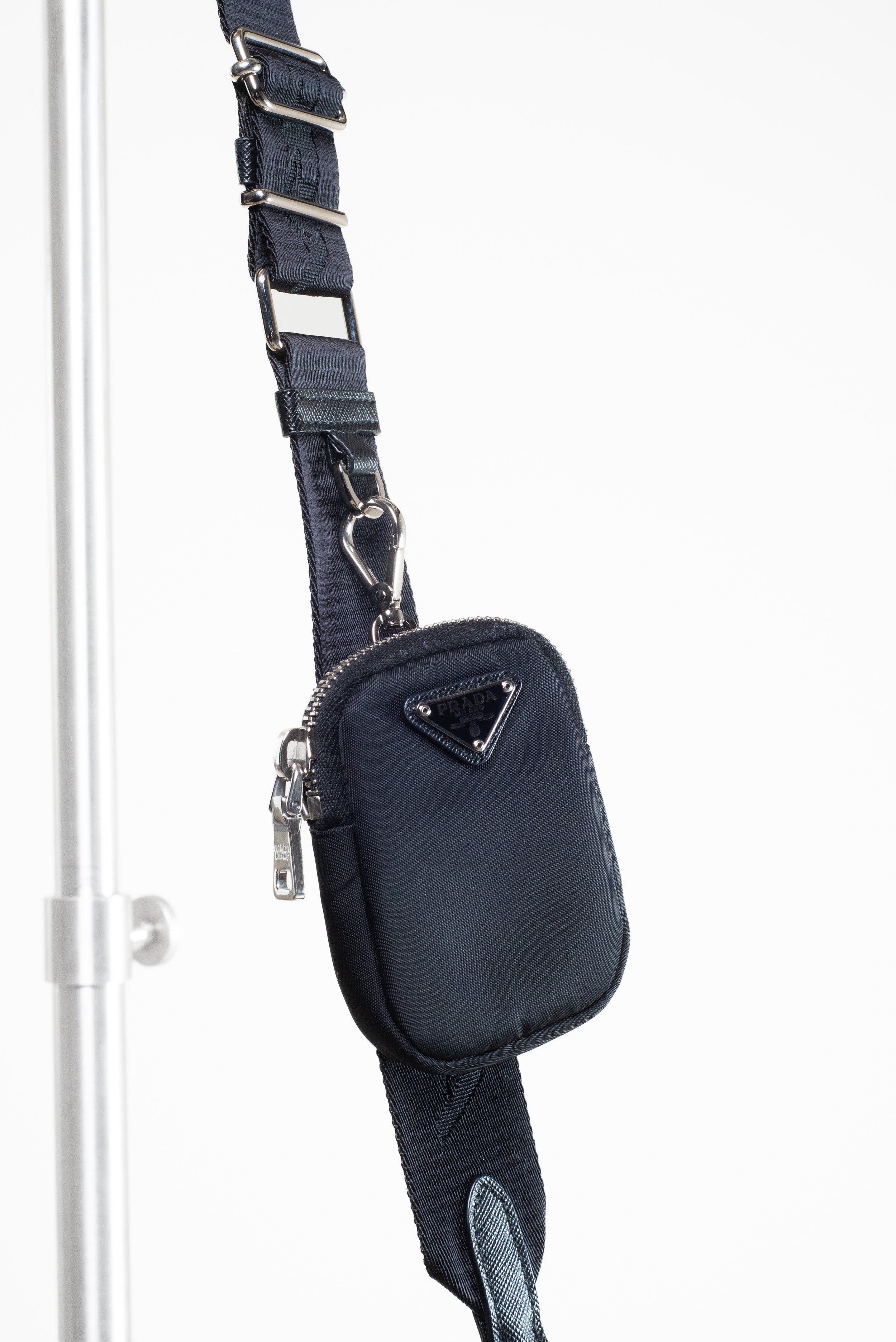 Detailed close-up of the small pouch attached to the strap of the Prada Black Re-Nylon and Saffiano Crossbody Bag