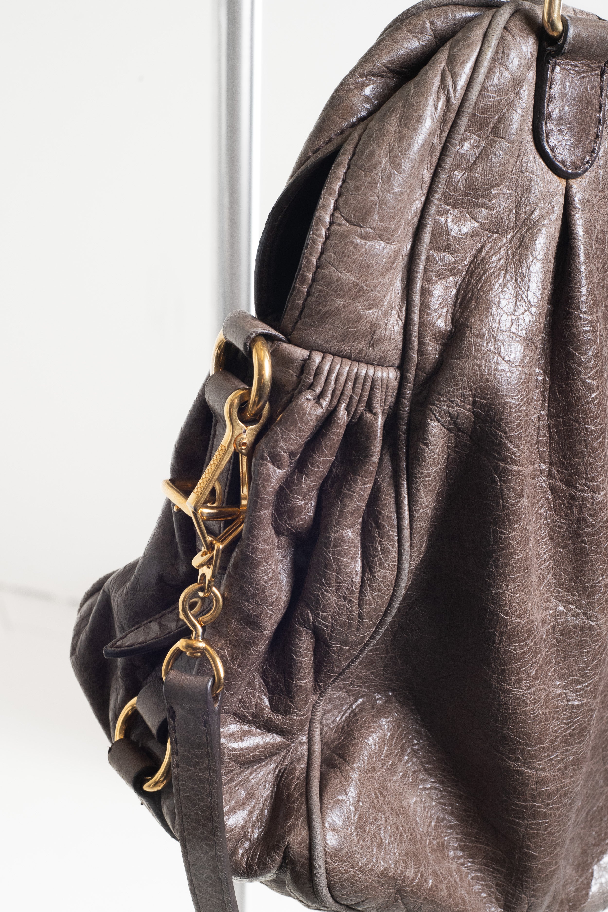 Detailed view of the strap connection and gold-tone hardware on the Miu Miu Brown Leather Gold Lock Bag