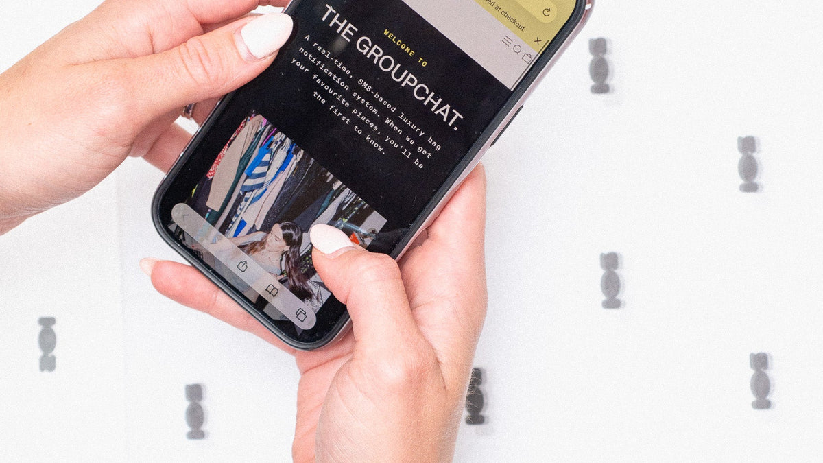 A person's hands holding a smartphone displaying a social media group chat screen, with a patterned white background.