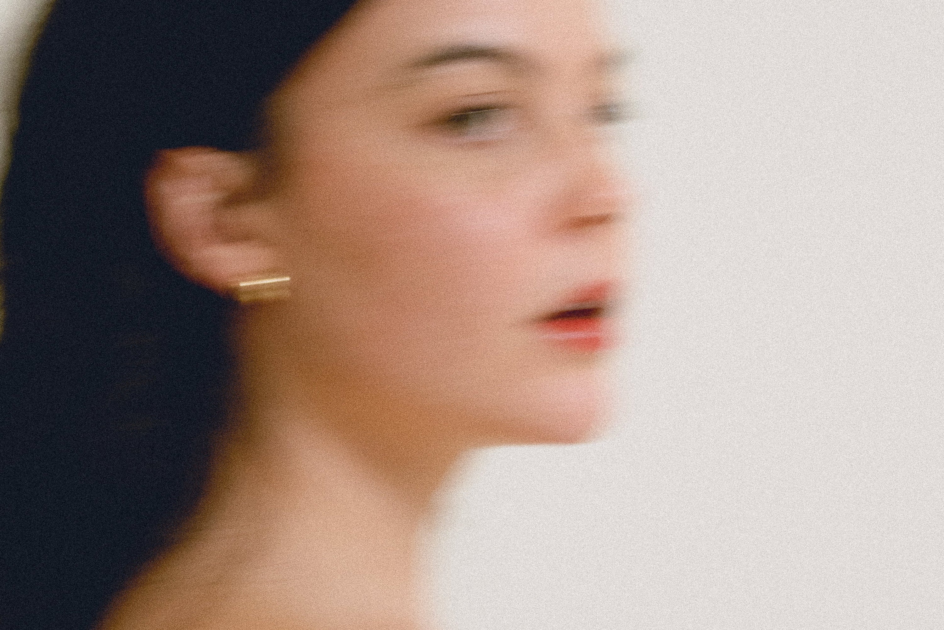 Woman with dark hair and earrings against a plain background