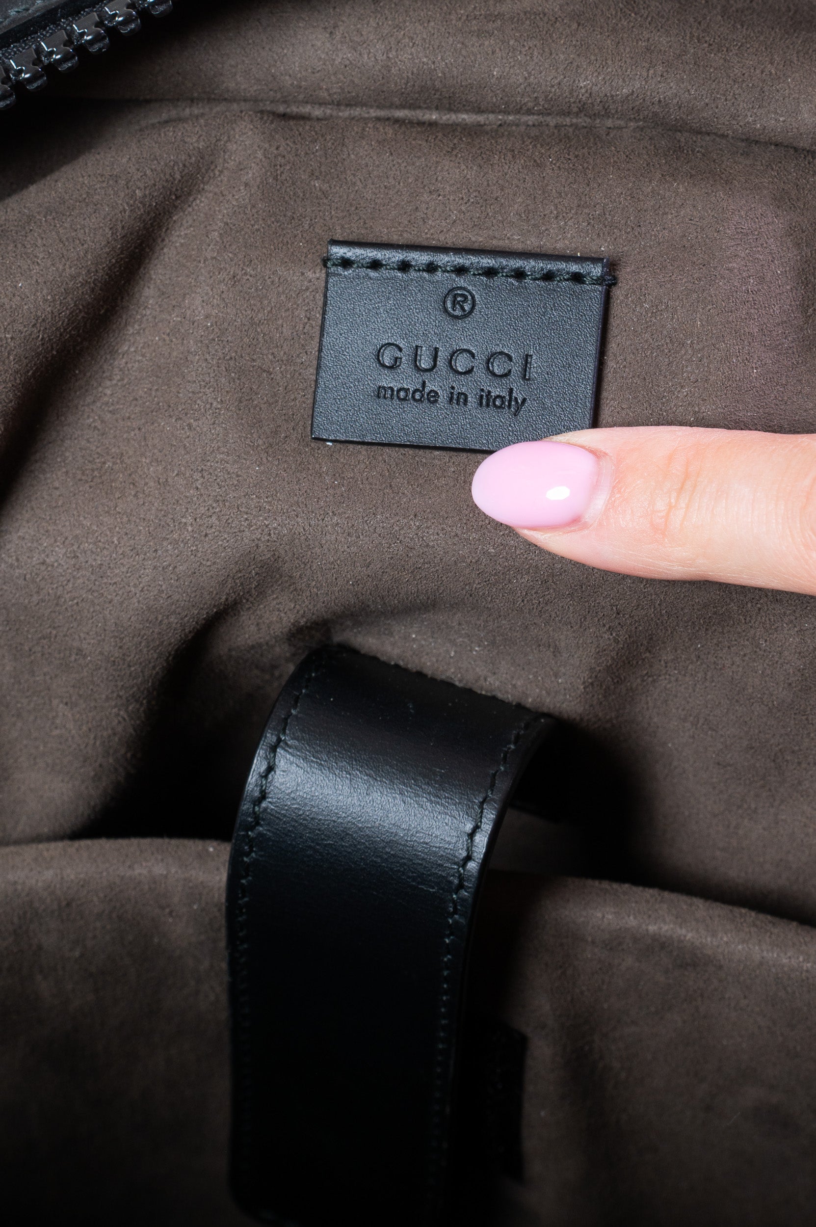 Interior view of Gucci Medium GG Coated Canvas Supreme Eden Backpack featuring embossed leather logo tag