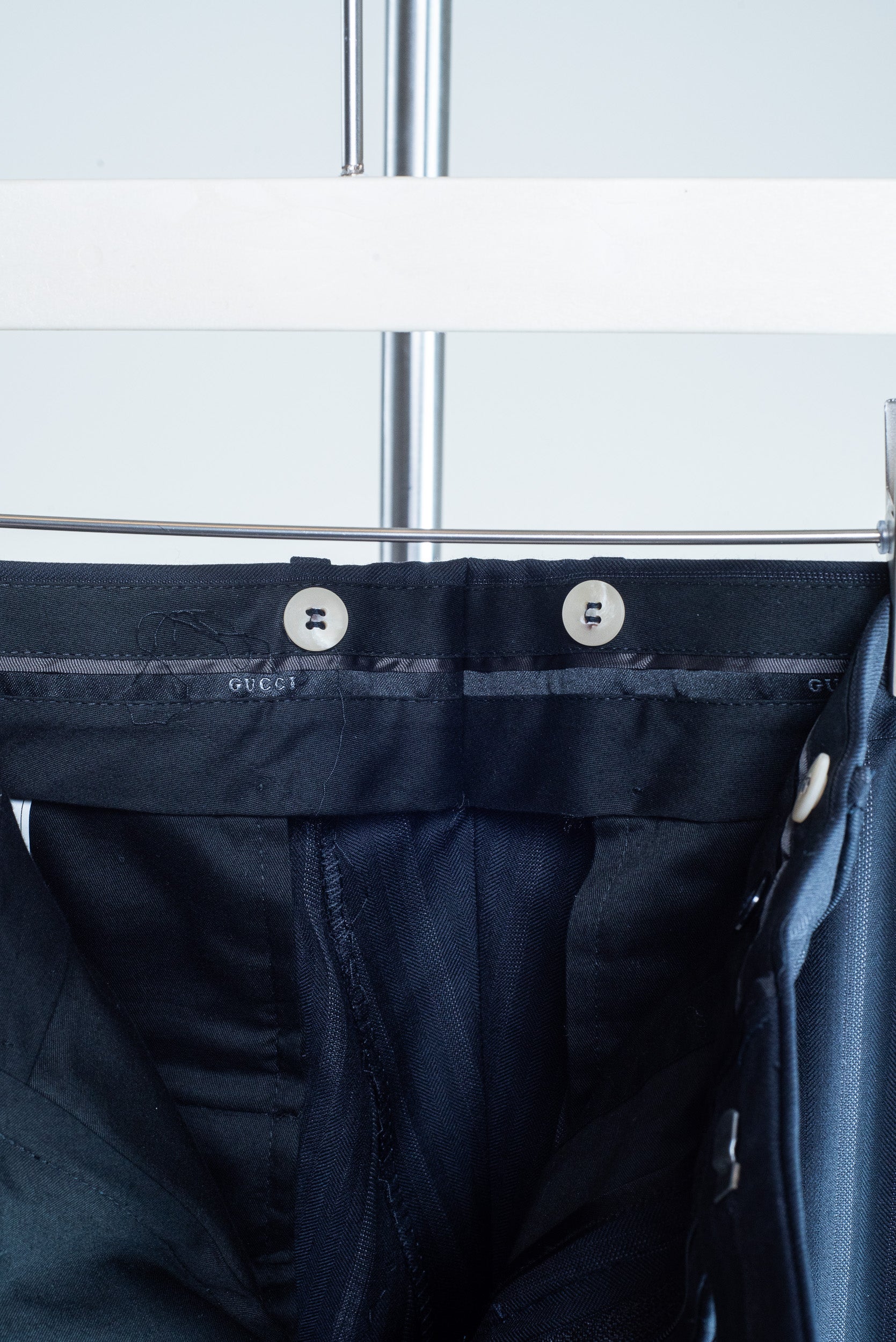 Detail of interior suspender buttons on Gucci pinstripe tailored pants